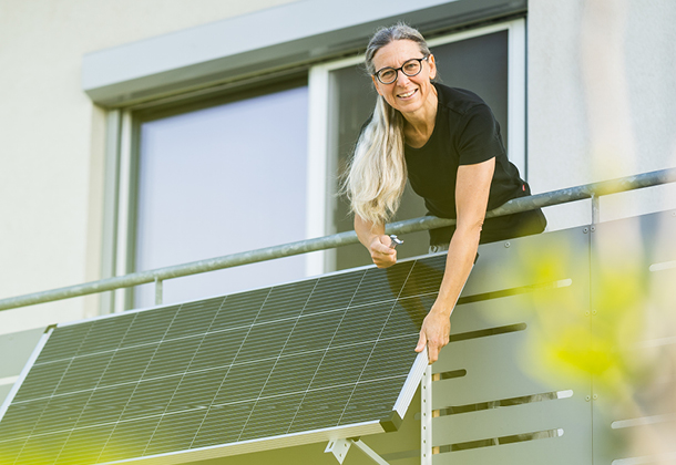 Eine Frau richtet ihr Balkonkraftwerk ein, eine mini Solaranlage