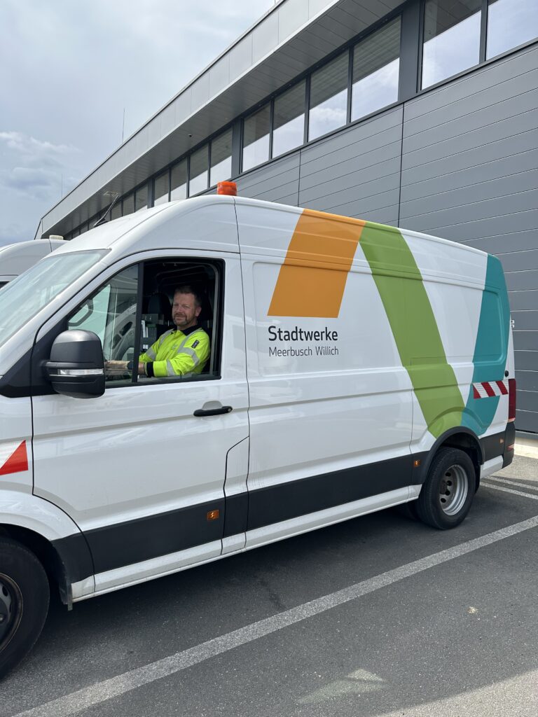 Mitarbeiter der Stadtwerke sitzt lächelnd im neu gestalteten Einsatzfahrzeug