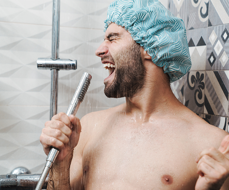 Mann mit Duschhaube singt unter der Dusche – Symbolbild für Sommer, Hitze und Wasserverbrauch