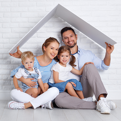 Eine junge Familie mit zwei Kindern sitzt unter einem symbolischen Dach und lächelt – Symbolbild für den Schutz und die Sicherheit der Ersatz- und Grundversorgung