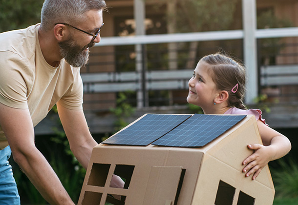 Vater und Tochter halten Solarmodul-Karton und lächeln sich an