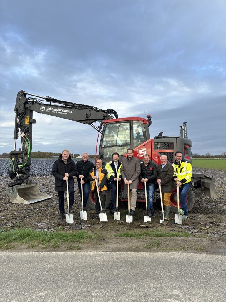 Spatenstich des Windparks Willich mit Stadtwerke-Team, Projektpartnern und Bagger auf dem Baugelände.