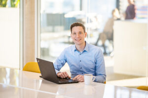 Mann mit Laptop in Gesprächssituation zur PFAS-Untersuchung und Wasserqualität