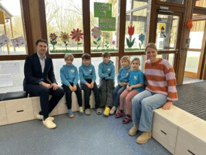 Gruppe von Personen sitzt um neue Holzsitzkisten in Schulaula