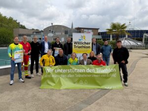 Gruppe vor de Bütt mit Banner der Stadtwerke Willich und Plakat zum Willicher Triathlon